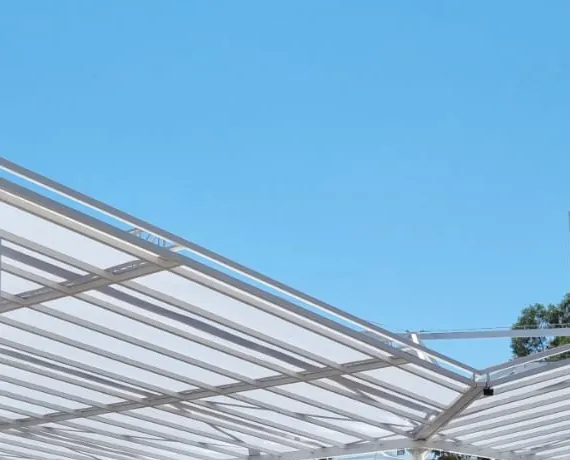 Cobertura translúcida em estrutura metálica branca contra o céu azul